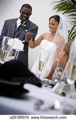 Stock Photo - Bride and groom cutting cake. Fotosearch