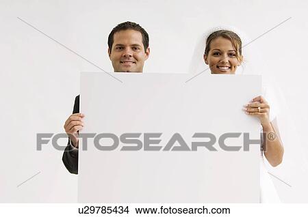 Picture - Bride and groom holding blank sign. Fotosearch