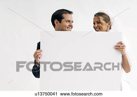 Bride and groom holding blank sign View Large Photo Image Stock Image - Bride and groom holding blank sign. Fotosearch