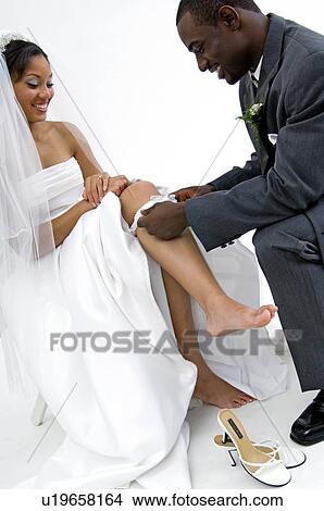 Picture - Groom taking off brides garter. Fotosearch
