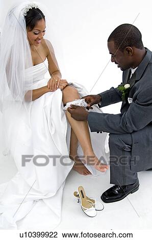 Stock Image - Groom taking off brides garter. Fotosearch