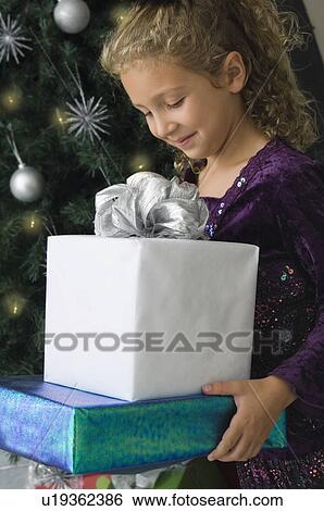Girl carrying Christmas gifts View Large Photo Image Stock Photograph - Girl carrying Christmas gifts. Fotosearch