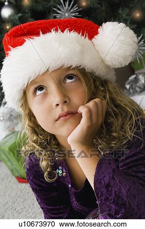 Stock Image - Girl wearing Santa hat. Fotosearch