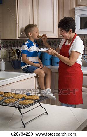 Stock Image - Grandma and grandson baking cookies. Fotosearch