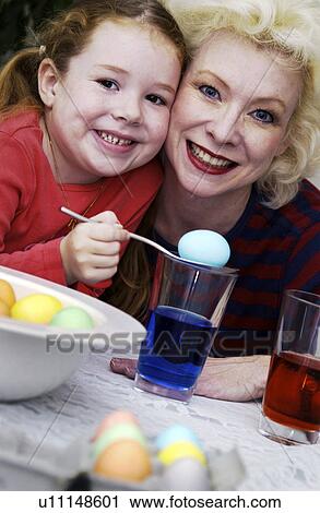 Stock Image - Mom and daughter dyeing Easter eggs. Fotosearch