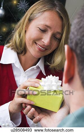 Man giving woman a Christmas gift View Large Photo Image Stock Image - Man giving woman a Christmas gift. Fotosearch