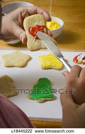 Stock Image - Mom and daughter decorating Christmas cookies. Fotosearch