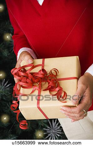 Stock Photo - Woman holding Christmas gift. Fotosearch
