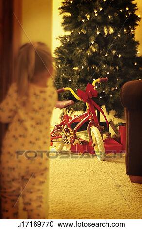 Stock Image - Girl peeking at Christmas tree. Fotosearch