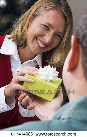 Stock Photograph - Man giving woman a Christmas gift. Fotosearch