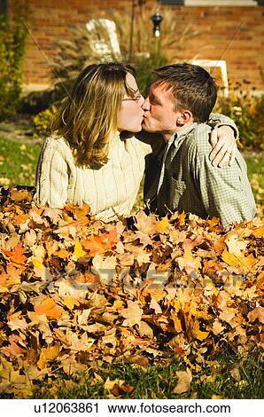 Stock Image - Couple playing in fall leaves. Fotosearch