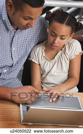 Stock Image - African American father helping daughter with homework. Fotosearch