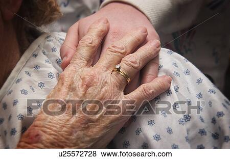 Stock Photo - Senior woman in wheelchair holding hands with nurse. Fotosearch