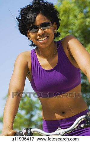 Stock Photo - African American woman riding bike. Fotosearch
