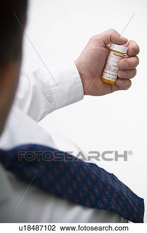 Stock Image - Man looking at prescription bottle. Fotosearch