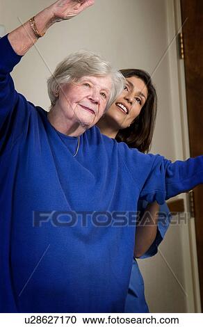Nurse helping senior woman with exercising View Large Photo Image Stock Image - Nurse helping senior woman with exercising. Fotosearch