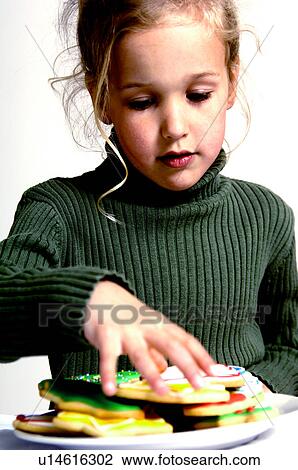 Girl taking a Christmas cookie from plate View Large Photo Image Stock Image - Girl taking a Christmas cookie from plate. Fotosearch