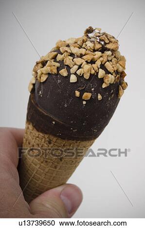 Stock Image - Man holding chocolate covered ice cream cone. Fotosearch
