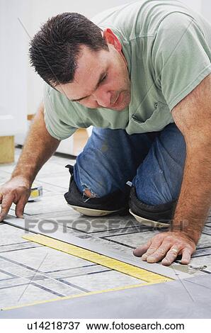 Stock Photo - Construction worker laying new flooring. Fotosearch