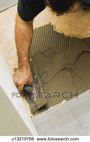 Stock Photograph - Construction worker laying subfloor. Fotosearch