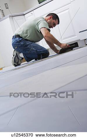 Stock Image - Construction worker laying tile. Fotosearch