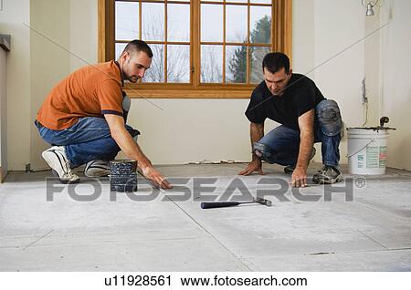 Stock Image - Construction workers laying subfloor. Fotosearch