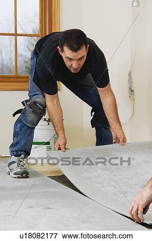 Stock Photo - Construction workers laying subfloor. Fotosearch