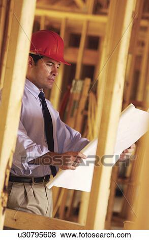 Stock Photo - Contractor looking over blueprints. Fotosearch