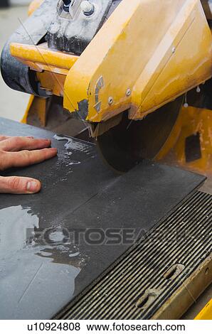 Stock Photo - Man cutting tile with saw. Fotosearch