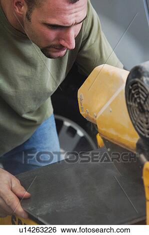 Stock Photograph - Man cutting tile with saw. Fotosearch