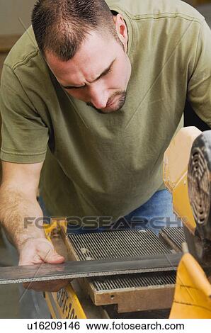 Stock Photograph - Man cutting tile with saw. Fotosearch