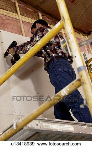 Man putting up drywall View Large Photo Image Stock Photo - Man putting up drywall. Fotosearch