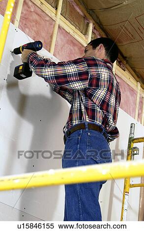 Stock Photography - Man putting up drywall. Fotosearch