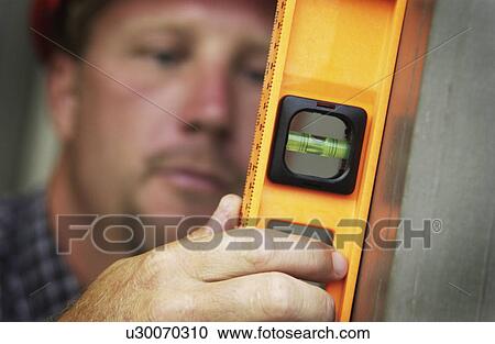 Stock Image - Man using level. Fotosearch