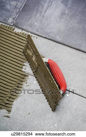Picture - Mortar, trowel and tile on subfloor. Fotosearch