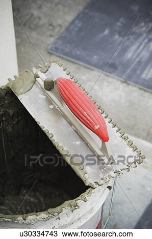 Stock Image - Mortar, trowel and tile on subfloor. Fotosearch