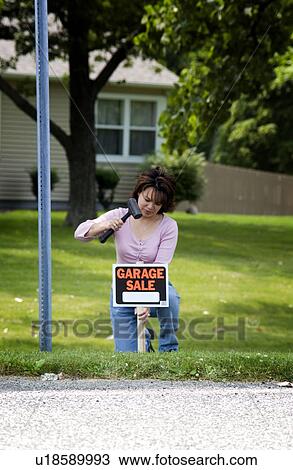 Woman putting up garage sale sign View Large Photo Image Stock Image - Woman putting up garage sale sign. Fotosearch