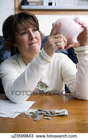 Woman raiding piggy bank View Large Photo Image Stock Image - Woman raiding piggy bank. Fotosearch