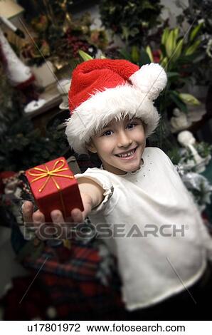 Girl in Santa hat holding gift View Large Photo Image Stock Image - Girl in Santa hat holding gift. Fotosearch