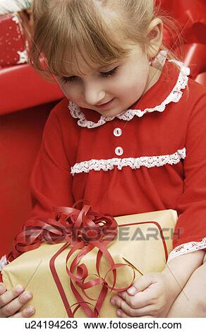 Stock Image - Girl opening a gift. Fotosearch