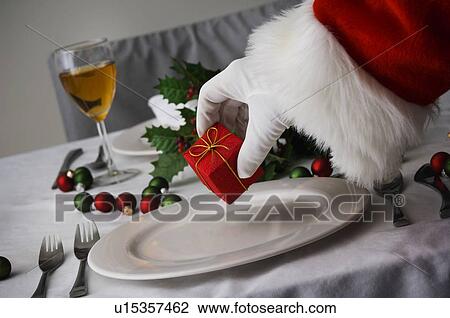 Stock Image - Santa setting gift on table. Fotosearch