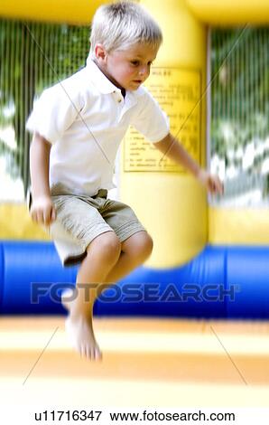 Stock Photo - Boy jumping on inflated trampoline. Fotosearch