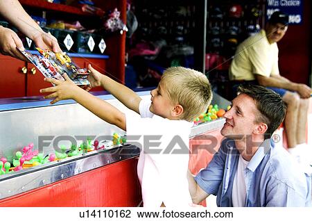 Stock Image - Father and son playing carnival game. Fotosearch