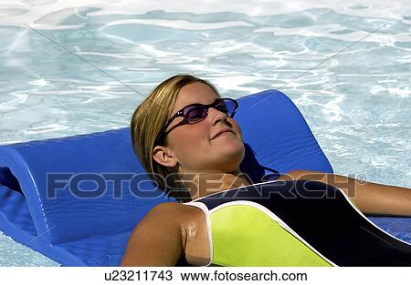 Stock Image - Woman lying on raft in pool. Fotosearch