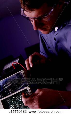 Stock Image - Technician repairing electronics item. Fotosearch