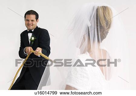 Stock Photo - Bride and groom playing tug of war. Fotosearch