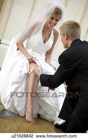 Stock Image - Groom taking off brides garter. Fotosearch
