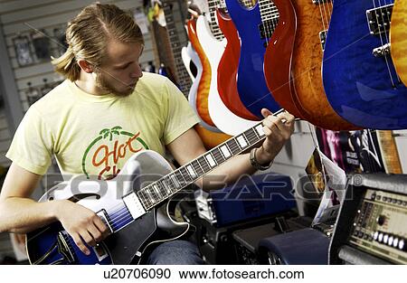 Stock Image - Man at guitar store. Fotosearch
