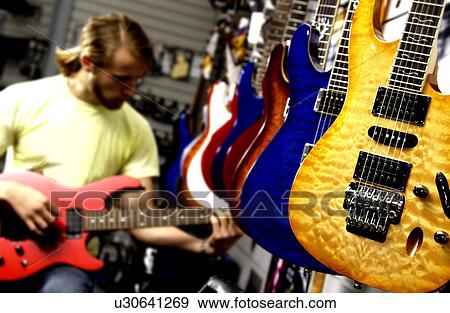 Stock Photo - Man at guitar store. Fotosearch