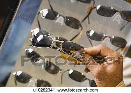 Stock Image - Man shopping for sunglasses. Fotosearch